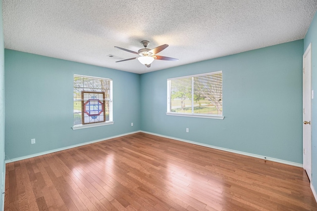 spare room with baseboards, plenty of natural light, a ceiling fan, and wood finished floors