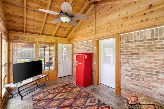 interior space featuring wooden walls, ceiling fan, lofted ceiling with beams, wooden ceiling, and wood finished floors
