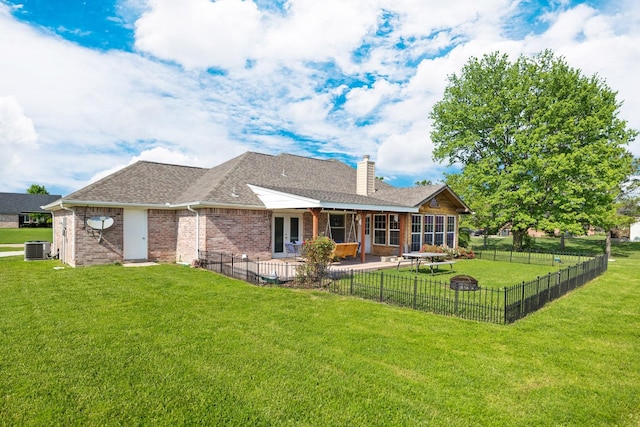 rear view of property with central AC, a patio, a fenced backyard, a chimney, and a yard