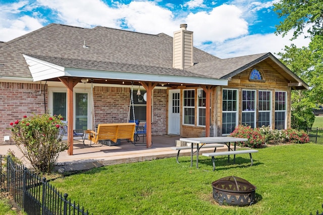 rear view of property featuring fence, a patio, a chimney, brick siding, and a lawn