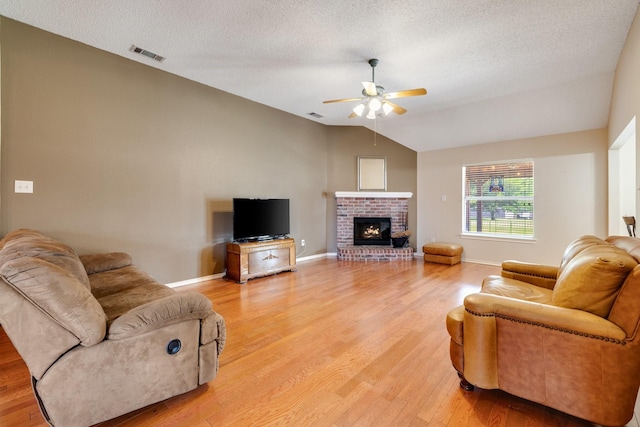 living room with a ceiling fan, visible vents, baseboards, lofted ceiling, and light wood-style floors