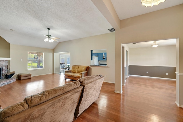 living area featuring wood finished floors, a fireplace, baseboards, ceiling fan, and vaulted ceiling
