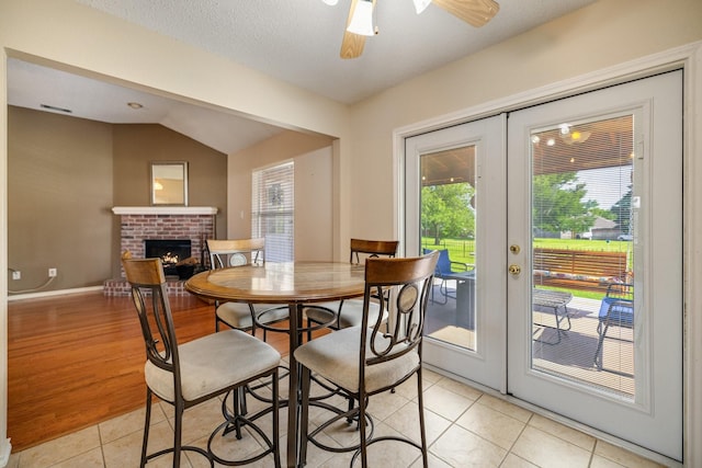 dining area with light tile patterned floors, a fireplace, french doors, and a wealth of natural light