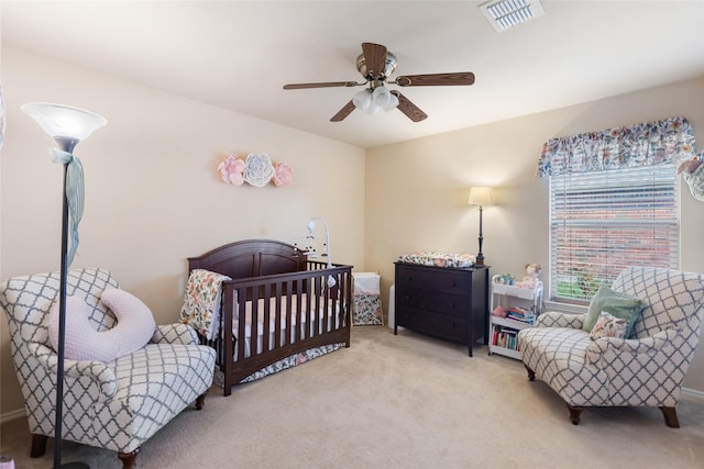 bedroom featuring a crib, ceiling fan, carpet, and visible vents