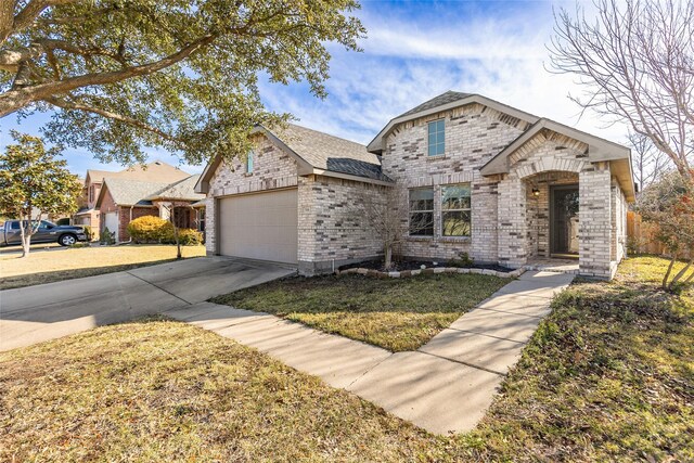 view of front of home with brick siding, an attached garage, a front yard, and concrete driveway
