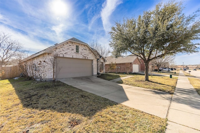 ranch-style house with concrete driveway, brick siding, fence, and a front yard