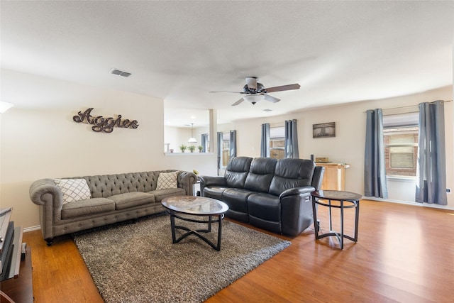 living area featuring visible vents, a ceiling fan, plenty of natural light, and wood finished floors
