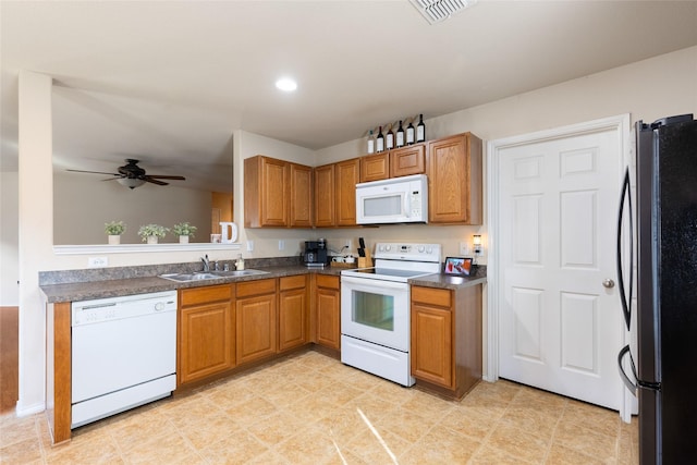 kitchen with a sink, dark countertops, brown cabinets, and white appliances