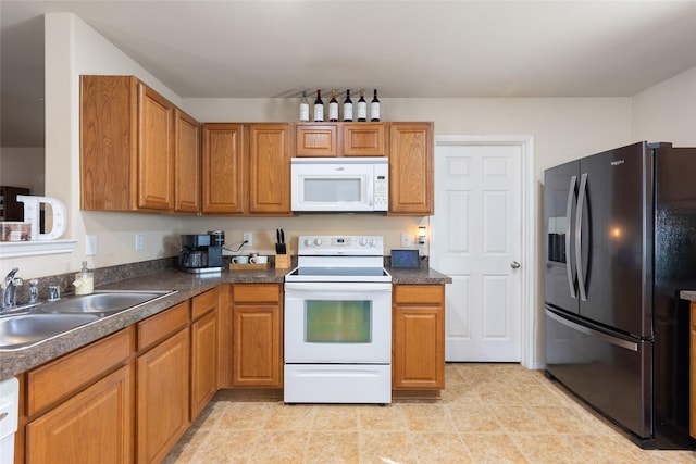 kitchen featuring a sink, brown cabinets, dark countertops, and white appliances