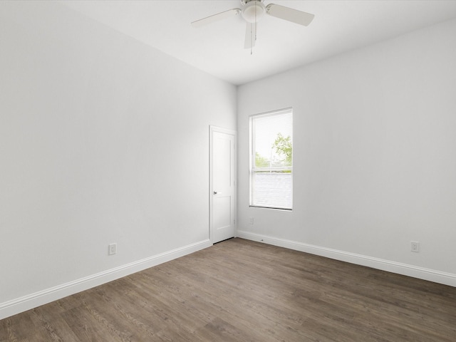 empty room with a ceiling fan, baseboards, and dark wood finished floors