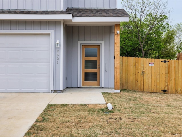 view of exterior entry featuring a lawn, board and batten siding, and fence
