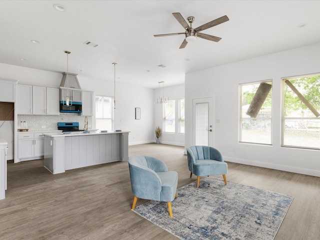 living room with baseboards, ceiling fan with notable chandelier, wood finished floors, and visible vents