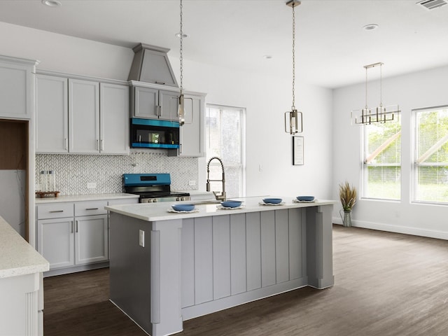 kitchen featuring backsplash, dark wood-style flooring, appliances with stainless steel finishes, and an island with sink