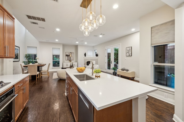 kitchen featuring brown cabinets, a sink, dark wood finished floors, stainless steel appliances, and open floor plan