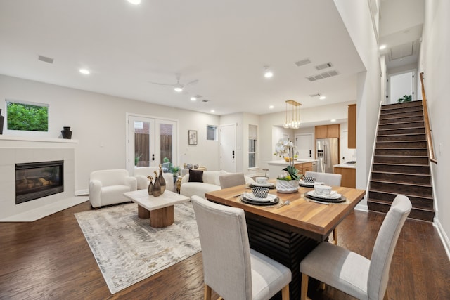 dining room featuring a healthy amount of sunlight, a fireplace, a ceiling fan, and dark wood finished floors