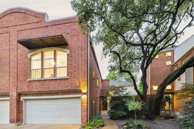 view of front of house featuring a garage, concrete driveway, and brick siding