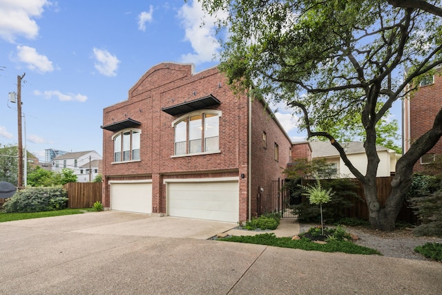 view of front of house featuring concrete driveway, brick siding, an attached garage, and fence