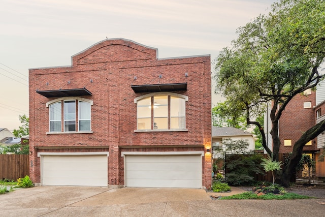 view of front of home featuring an attached garage, fence, driveway, and brick siding