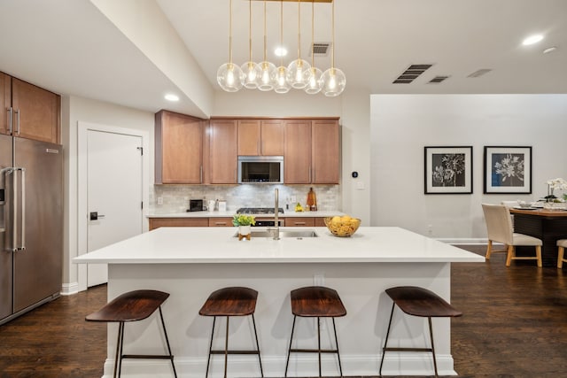 kitchen with brown cabinetry, a sink, a kitchen breakfast bar, and stainless steel appliances