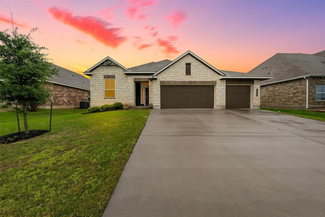 ranch-style home with central AC, stone siding, a garage, a front yard, and driveway