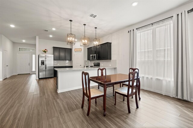 dining space with recessed lighting, visible vents, wood finished floors, and an inviting chandelier