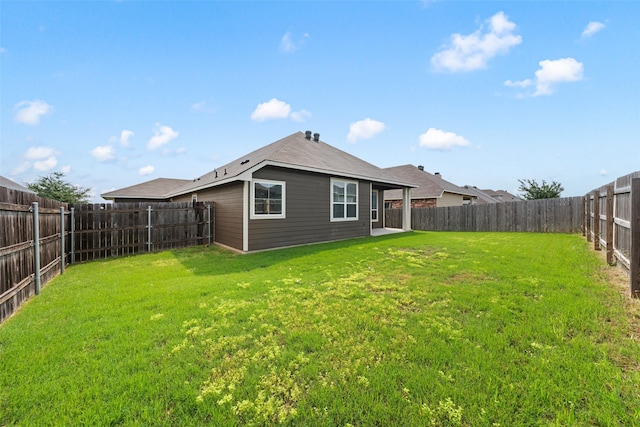 back of house featuring a fenced backyard and a lawn