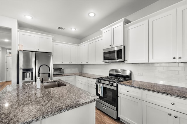 517 Williams Way, Van Alstyne, TX 75495 - kitchen with visible vents, appliances with stainless steel finishes, wood finished floors, a sink, and white cabinetry