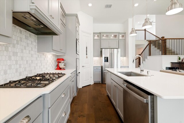 kitchen with visible vents, light countertops, custom range hood, a sink, and appliances with stainless steel finishes