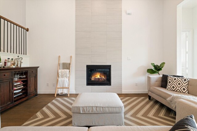 living room with baseboards, a tiled fireplace, wood finished floors, and a dry bar