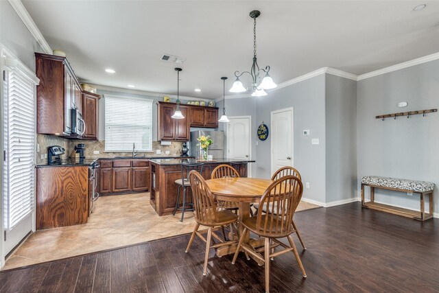 dining room featuring visible vents, ornamental molding, baseboards, light wood-type flooring, and a notable chandelier