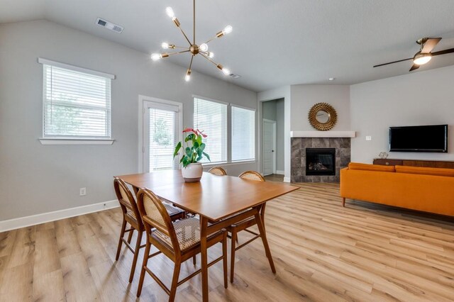 dining area with plenty of natural light, light wood-style flooring, a tile fireplace, and visible vents