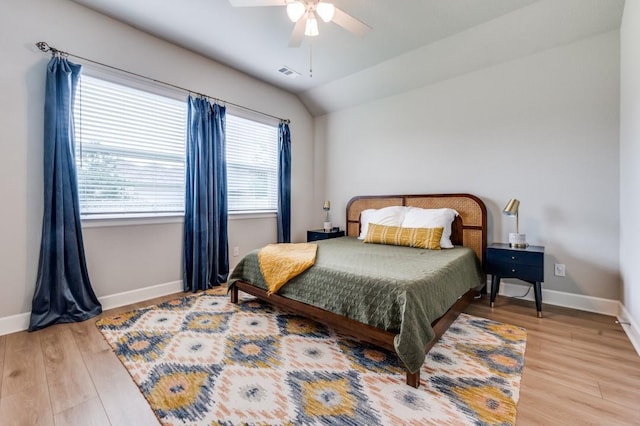 bedroom with visible vents, light wood-style flooring, lofted ceiling, and baseboards
