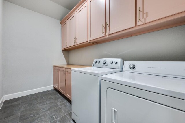 laundry area featuring separate washer and dryer, baseboards, and cabinet space