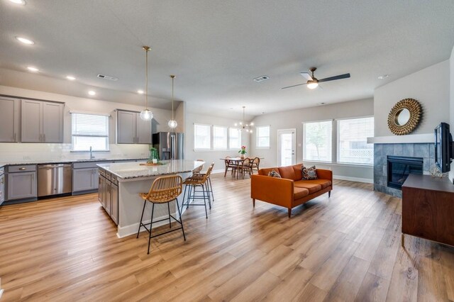 kitchen featuring a breakfast bar, light wood-style floors, a sink, appliances with stainless steel finishes, and gray cabinetry
