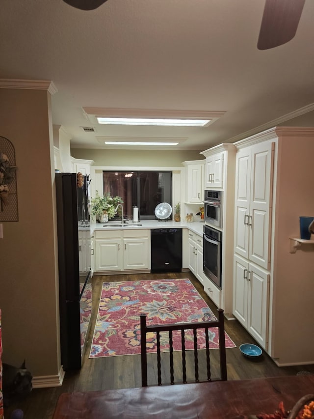 kitchen featuring visible vents, dark wood finished floors, a sink, light countertops, and black appliances