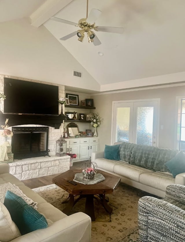 living area with ceiling fan, a stone fireplace, visible vents, high vaulted ceiling, and beamed ceiling
