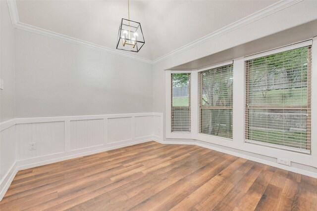 unfurnished room featuring wainscoting, a notable chandelier, ornamental molding, and wood finished floors