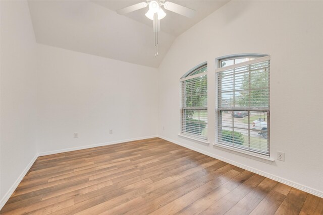 empty room with light wood-style floors, baseboards, vaulted ceiling, and a ceiling fan