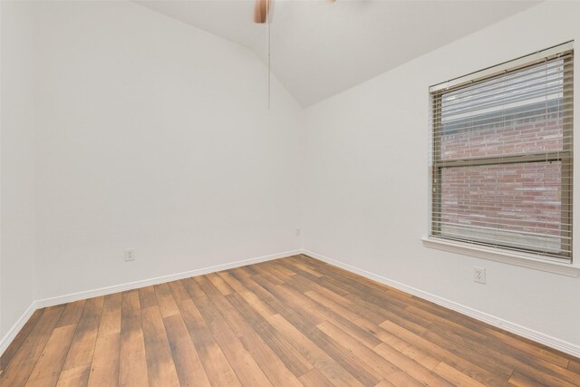 spare room with hardwood / wood-style floors, a wealth of natural light, baseboards, ceiling fan, and vaulted ceiling