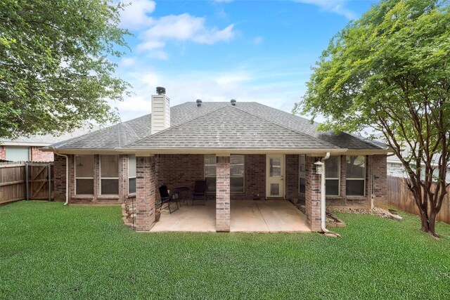 rear view of property with a lawn, a shingled roof, a fenced backyard, and brick siding