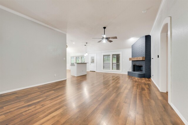 unfurnished living room featuring ceiling fan, crown molding, a fireplace, baseboards, and dark wood-type flooring