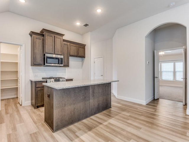 2012 Ranchwood Dr, Wylie, TX 75098 - kitchen with stainless steel appliances, arched walkways, light wood finished floors, a center island, and recessed lighting