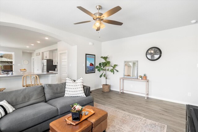 living area featuring wood finished floors, baseboards, recessed lighting, arched walkways, and a ceiling fan