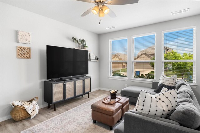 living area with baseboards, ceiling fan, visible vents, and wood finished floors
