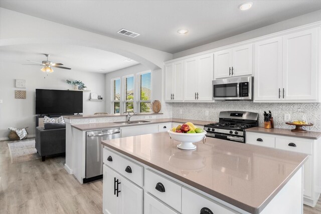 kitchen with visible vents, arched walkways, a center island, a sink, and stainless steel appliances