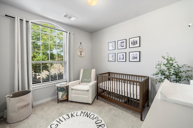 bedroom featuring a crib, multiple windows, carpet, and visible vents