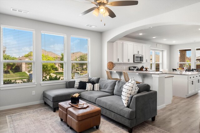 living area with visible vents, light wood-style flooring, ceiling fan, and baseboards