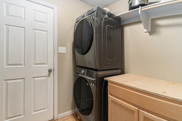 303 Valley View Ct, Rio Vista, TX 76093 - washroom with light tile patterned floors, stacked washer and dryer, cabinet space, and baseboards
