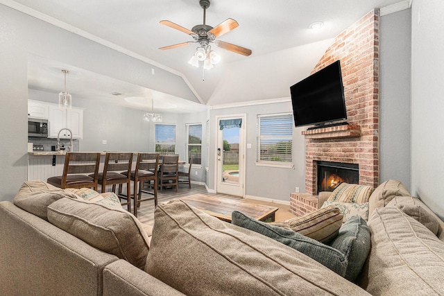 303 Valley View Ct, Rio Vista, TX 76093 - living area with lofted ceiling, light wood-style flooring, ornamental molding, ceiling fan with notable chandelier, and a fireplace