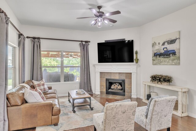 living area with baseboards, a ceiling fan, wood finished floors, and a fireplace